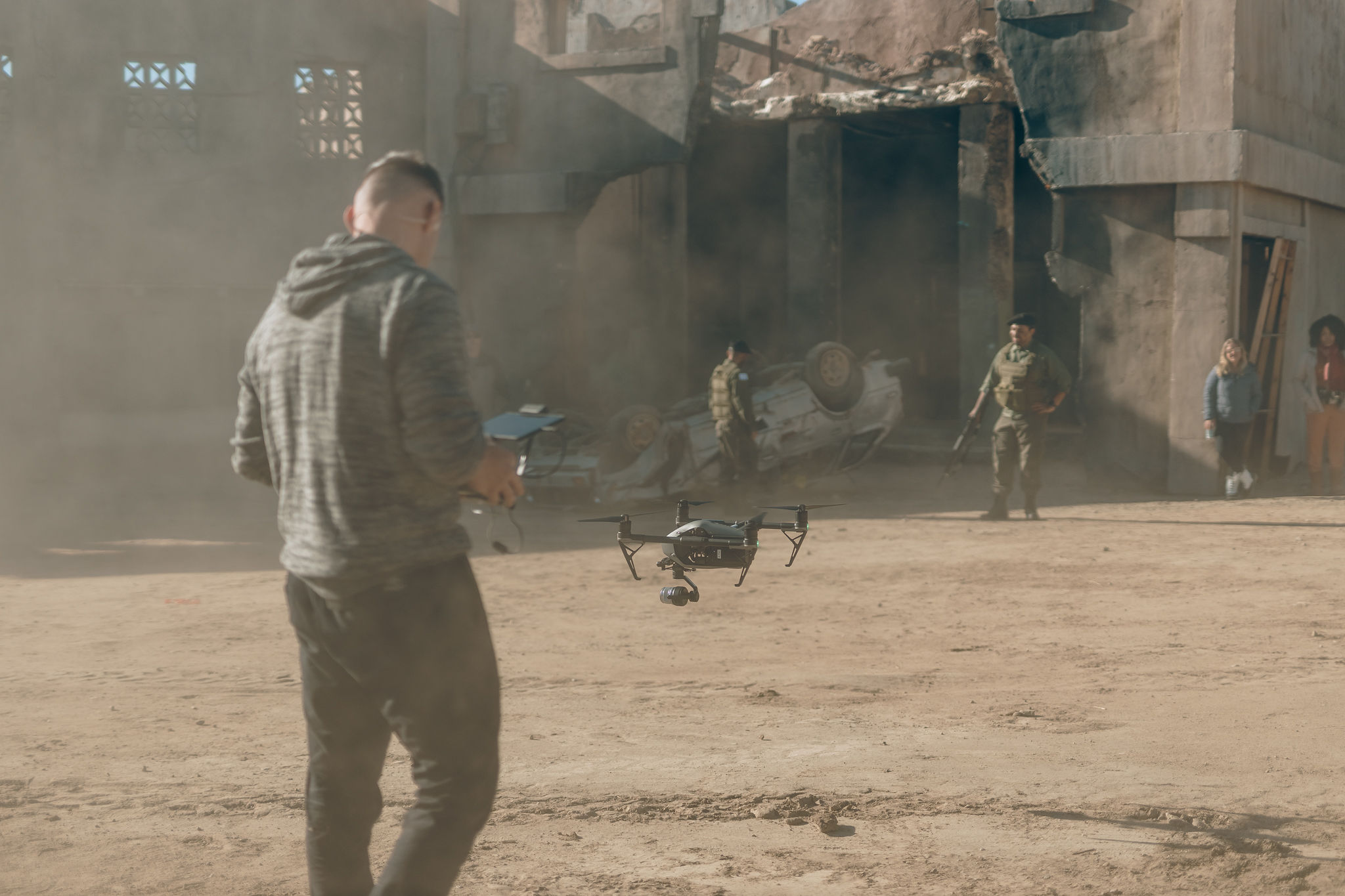 A camera operator moving through a dusty exterior scene