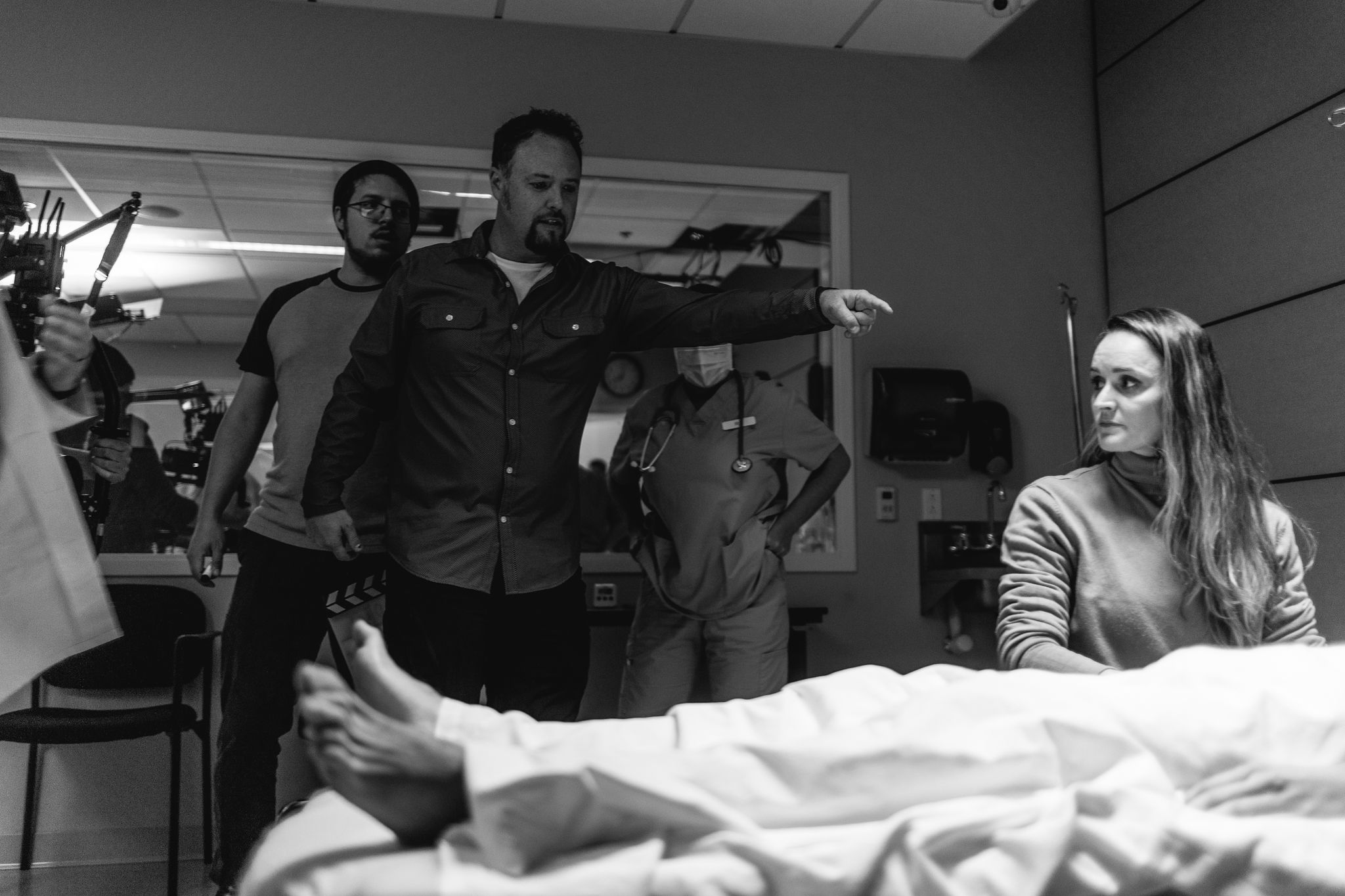 Wayne directing a performance on an interior set, photographed in black and white