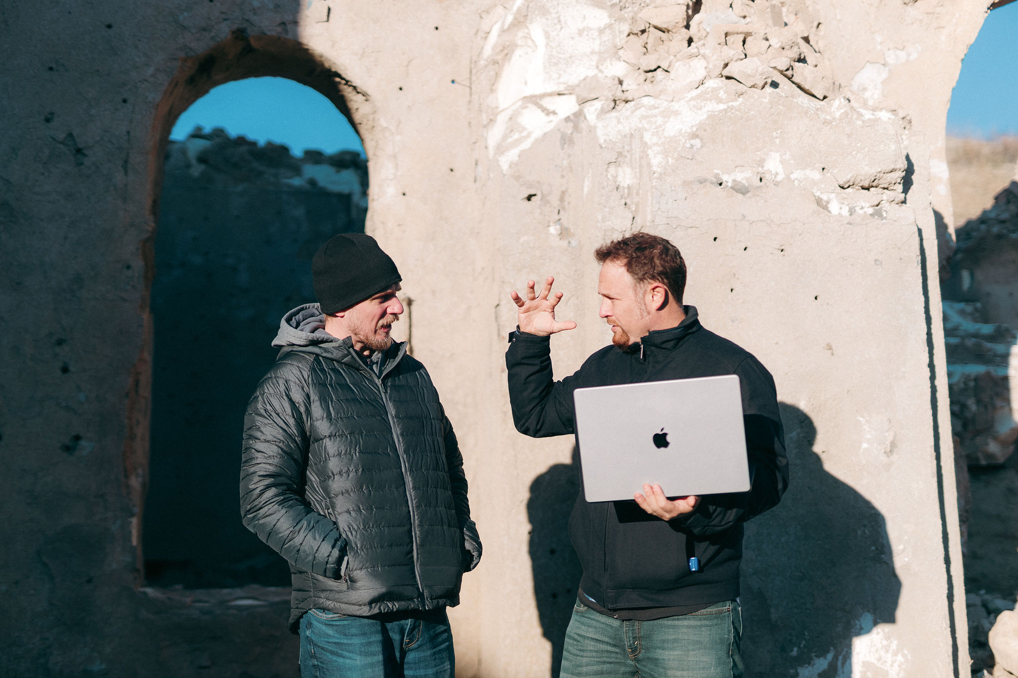 Wayne holding a laptop and discussing the creative vision with a colleague on location
