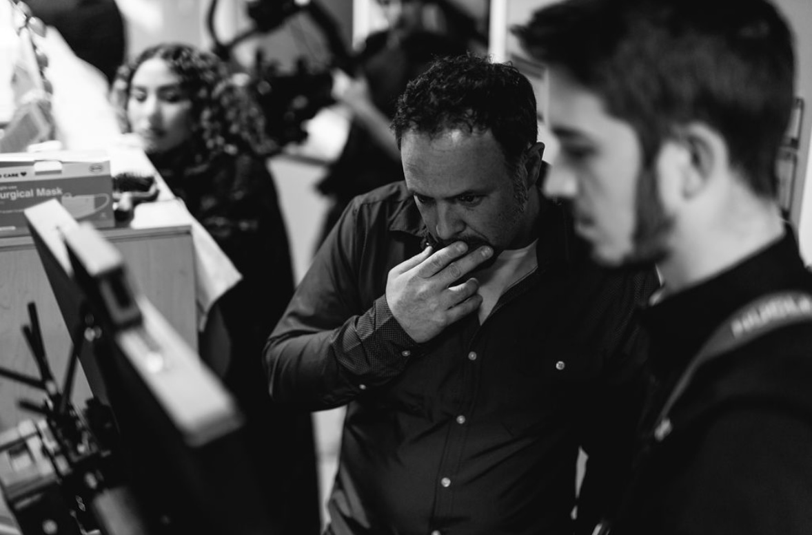 Black-and-white photograph of Wayne studying production monitors with his crew